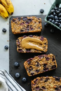 blueberry bread with peanut butter on top next to some bananas and other food items