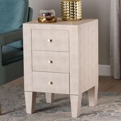 a white night stand with two drawers and a blue chair in the background