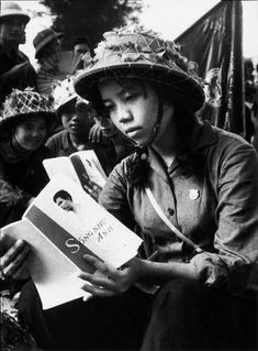 an old photo of a woman reading a book with other people in the back ground