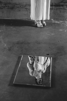 a black and white photo of someone's feet in front of a mirrored surface