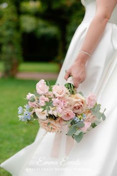 a woman in a white dress holding a bouquet of pink and blue flowers on her wedding day