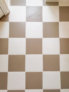 a white toilet sitting next to a window on top of a checkered tile floor