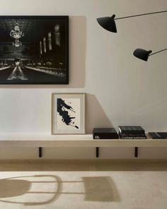 a white shelf with some books on it next to a black and white photograph hanging above