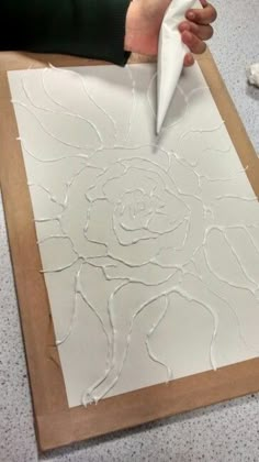 someone is using a paper towel to make a flower design on a piece of wood