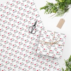 wrapping paper with the words dad on it and scissors next to it, surrounded by greenery