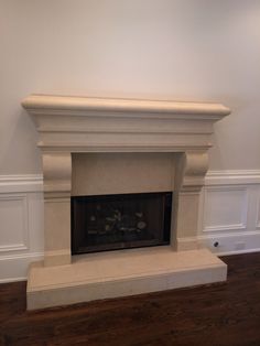 an empty fireplace in the corner of a room with white walls and wood flooring