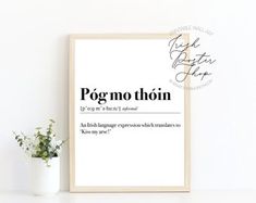 a white framed poster with the words pogmo thon on it next to a potted plant