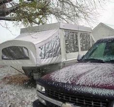 a truck covered in snow parked next to a house with a tarp over it