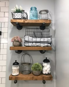 three wooden shelves with wire baskets and jars on them in a white tiled shower stall