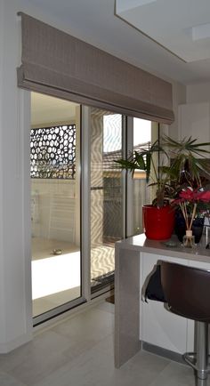 a kitchen area with a counter, potted plants and sliding glass doors