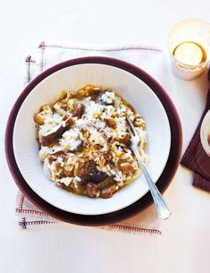 a white bowl filled with food on top of a table next to a glass of orange juice