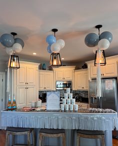 a kitchen filled with lots of counter top space and lights hanging from the ceiling above it