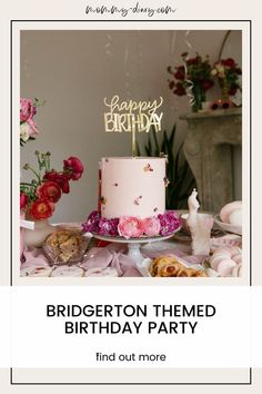 a pink birthday cake sitting on top of a table next to flowers and other decorations