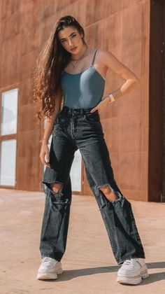 a woman standing in front of a building with her hands on her hips and looking at the camera