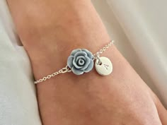 a person wearing a bracelet with a flower on the side and a heart charm attached to it