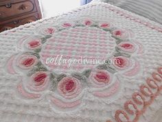 a crocheted bedspread with pink and white flowers on the edges that spell goodbye