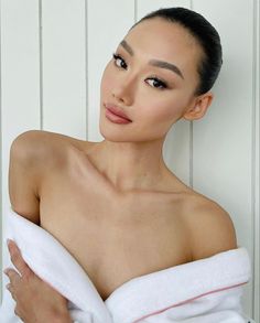 a woman in a towel is posing for the camera with her hand on her shoulder