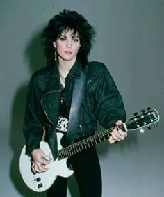 a woman with black hair holding an electric guitar