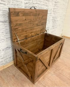 a wooden box sitting on top of a hard wood floor next to a brick wall