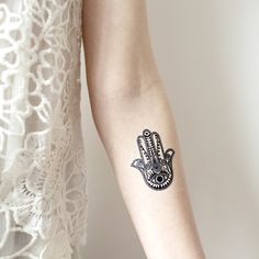 a woman's arm with a tattoo on it that looks like a hamsa hand