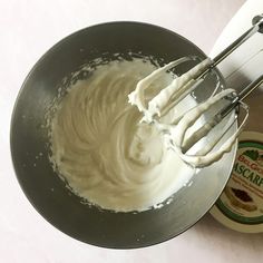 a metal bowl filled with whipped cream next to a bottle of mayonnaise and a whisk