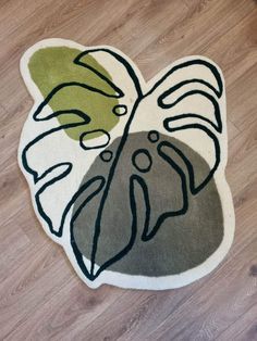 a close up of a rug on a wooden floor with a plant in the middle