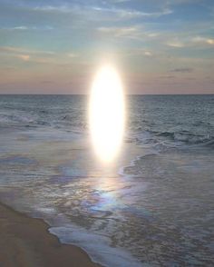 the sun is setting over the ocean with waves crashing on the beach and an object in the air