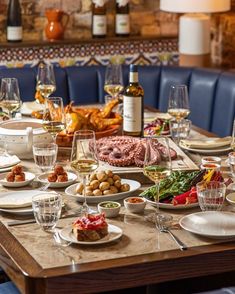 a dining table is set with food and wine glasses on it, along with other dishes