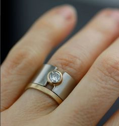 a close up of a person's hand wearing a ring with a diamond on it