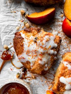 an apple scones with white icing and some fruit next to it on a piece of parchment paper