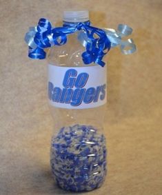 a bottle with blue and white confetti in it sitting on the floor next to a ball