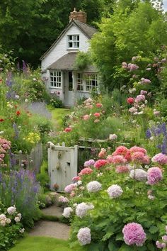 a garden filled with lots of flowers next to a white house on top of a lush green hillside