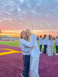 two women hugging each other on the field