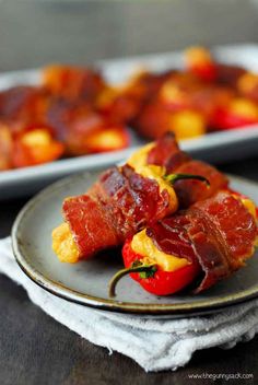 bacon wrapped peppers on a plate with other food items in the backgroung