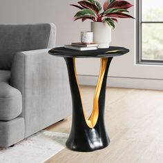 a black and gold side table with a potted plant on it in front of a couch