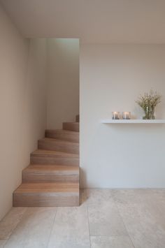 some candles are sitting on top of the stairs in this room with white walls and tile flooring