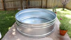 a metal tub sitting on top of a cement slab next to a potted plant