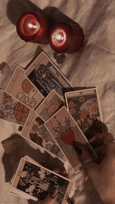 candles and cards are on the table with two hands holding them