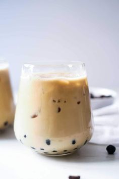 two glasses filled with liquid sitting on top of a white table next to each other