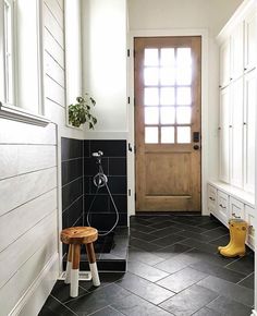 a black and white tiled bathroom with a wooden door, stools, and potted plant