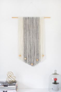 a macrame wall hanging on a white wall next to a vase with flowers