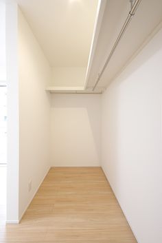 an empty room with white walls and wood flooring is pictured in this image from the corner