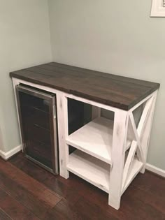 a white and brown wooden cabinet sitting on top of a hard wood floor next to a wall