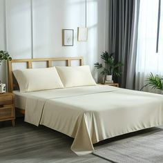 a bed with white sheets and pillows in a room