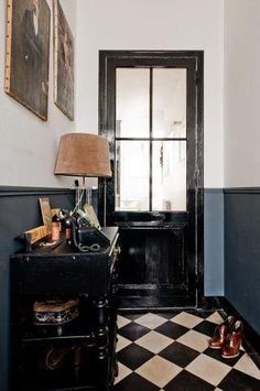 a black and white checkered floor in a room with a lamp on the end table