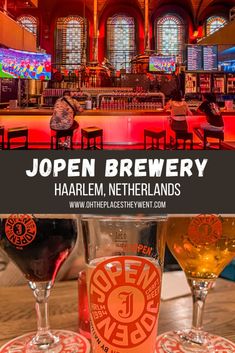 two glasses of beer sitting on top of a table in front of a bar with neon lights