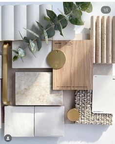 some white and gold items are arranged on top of each other, including tiles, wood, and plants