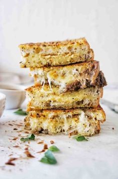 three pieces of grilled cheese sandwich stacked on top of each other next to a white bowl