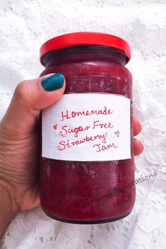 a hand holding a jar of homemade sugar free strawberry jam with a note attached to it