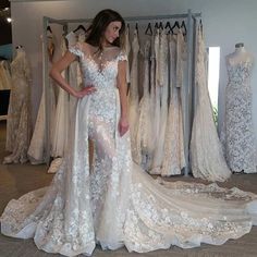 a woman is standing in front of dresses on display at a bridal shop and posing for the camera